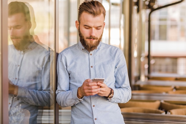 Free photo young man using smartphone in restaurant