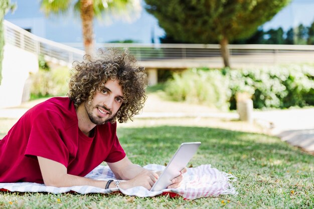 Young man using tablet on park ground