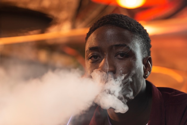 Free photo young man vaping from a hookah in a bar