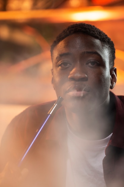 Free photo young man vaping from a hookah in a bar