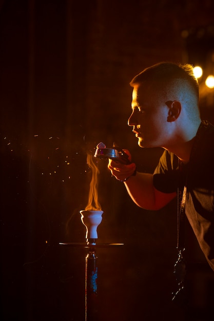 Young man vaping from a hookah in a bar