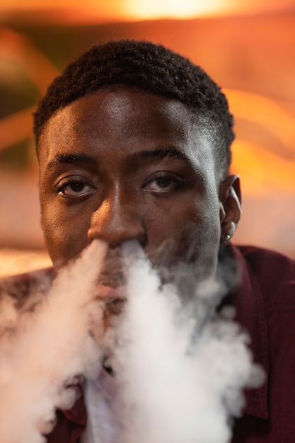 Free photo young man vaping from a hookah in a bar