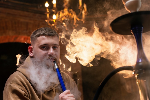 Free Photo young man vaping from a hookah in a bar