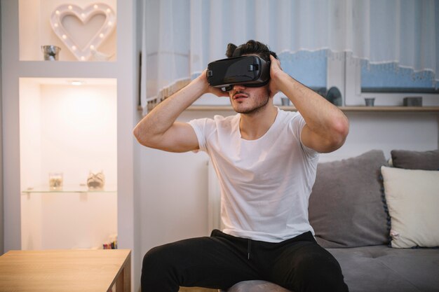 Young man in VR glasses on sofa