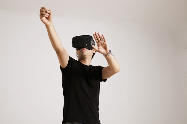 A young man in VR headset wearing plain black cotton t-shirt interacting with his environment isolated on white