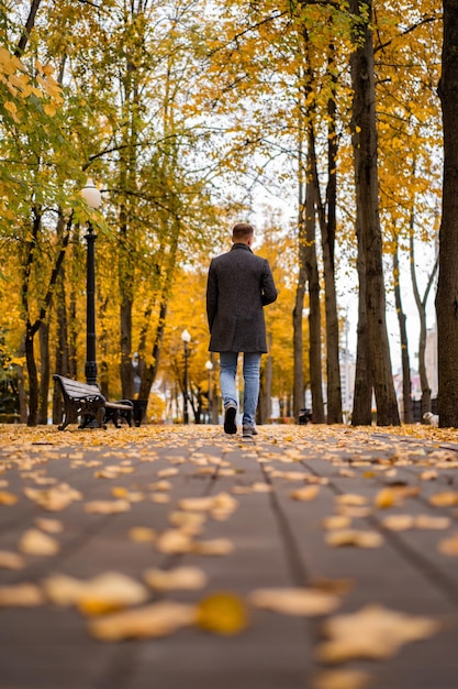 Young man walking in the autumn city with a glass of coffee