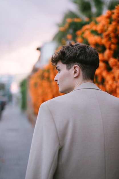 Free photo behind the young man walking near flowers