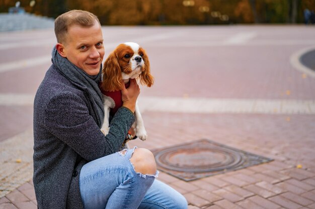 Young man walking with a dog in the autumn park