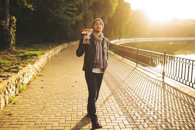 Young man walks by the lake and holding guitar