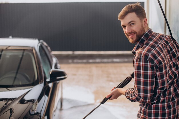 Free photo young man washing his car at carwash