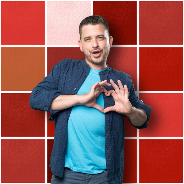 Free photo young man wearing a blue outfit. doing a heart gesture.