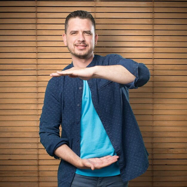 Young man wearing a blue outfit. Doing a holding gesture.