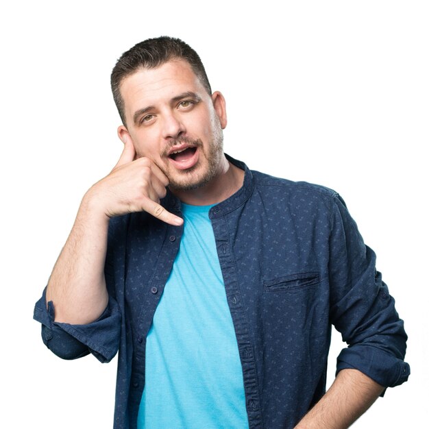 Free photo young man wearing a blue outfit. doing telephone gesture.