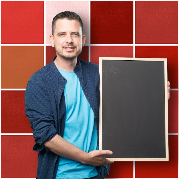 Free photo young man wearing a blue outfit. holding a blackboard.