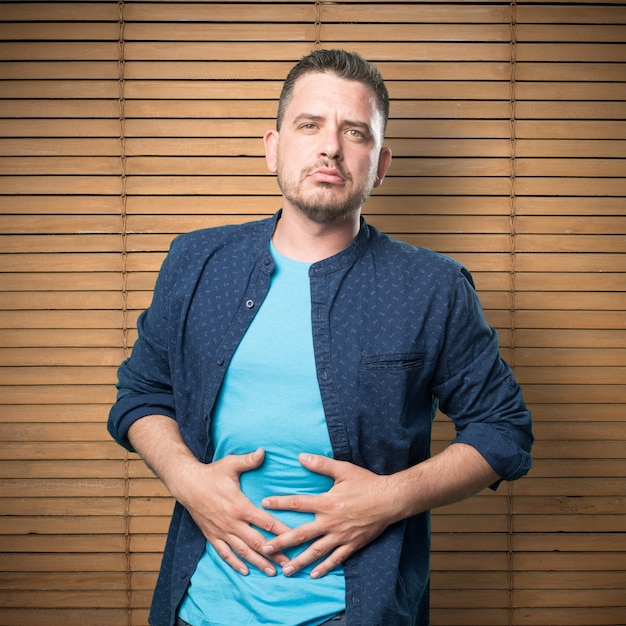 Free photo young man wearing a blue outfit. wit stomachache.