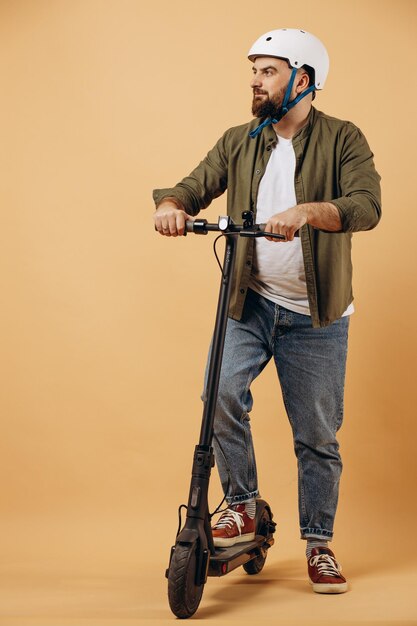 Young man wearing safety helmet and riding electric scooter