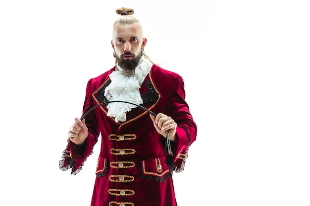 The young man wearing a traditional medieval costume of marquis posing at studio with whip