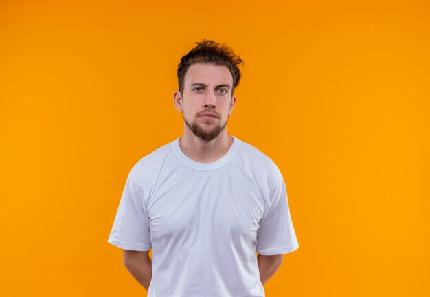  young man wearing white t-shirt put his hands on back on isolated orange wall