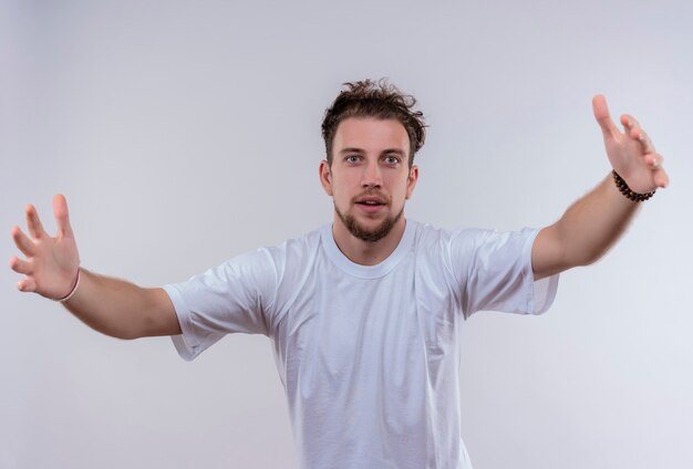  young man wearing white t-shirt showing size on isolated white wall