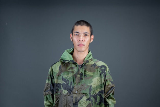 Free photo the young man wears a camouflage raincoat and shows different gestures.