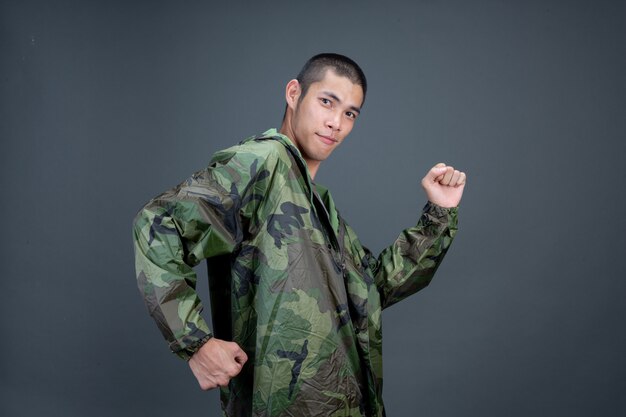 The young man wears a camouflage raincoat and shows different gestures. 