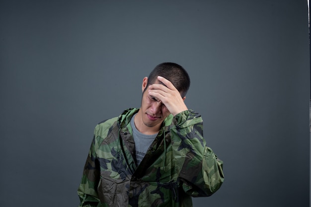 The young man wears a camouflage raincoat and shows different gestures. 