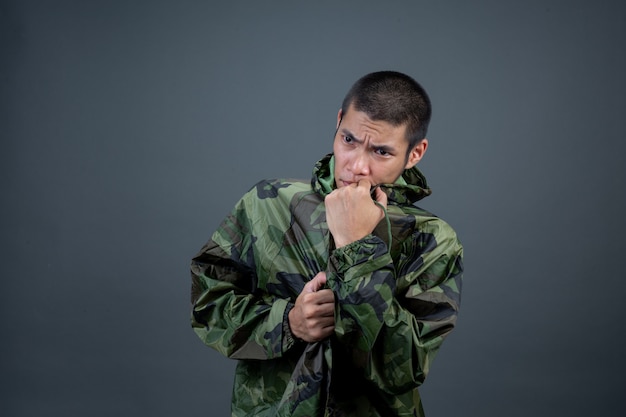 The young man wears a camouflage raincoat and shows different gestures. 