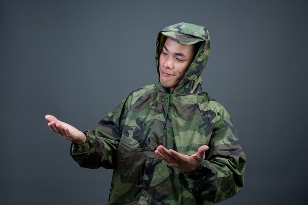 The young man wears a camouflage raincoat and shows different gestures. 