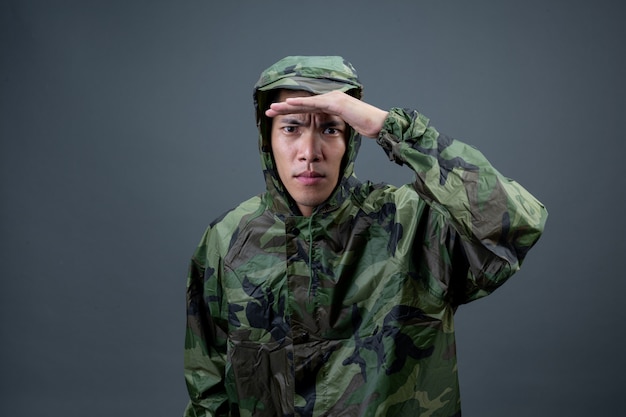 The young man wears a camouflage raincoat and shows different gestures. 