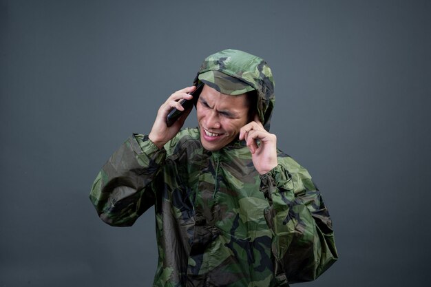 The young man wears a camouflage raincoat and shows different gestures. 