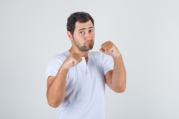 Young man in white t-shirt posing as a boxer and looking strong