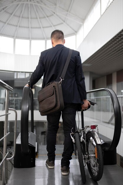 Free photo young man with folding bike on escalator