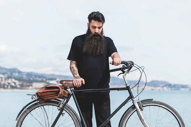 Young man with his bicycle standing near the coast