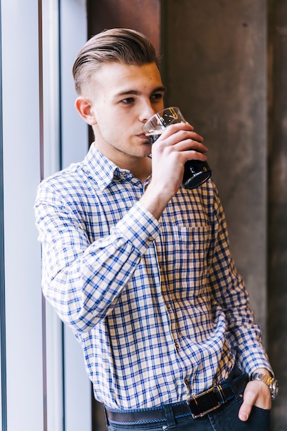 Young man with his hand in pocket drinking the beer