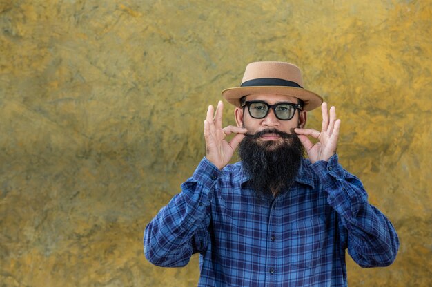 Young man with a long beard wearing a hat and glasses