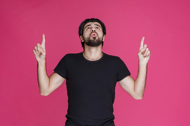 Free Photo young man with long hairs and beard showing or pointing at something with his fingers.