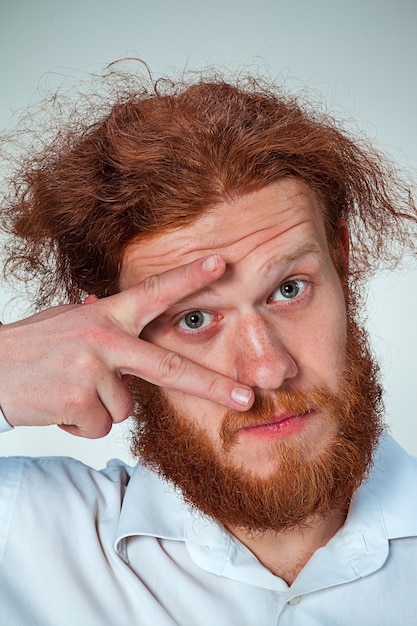 Free Photo the young man with long red hair looking at camera, opening his eye