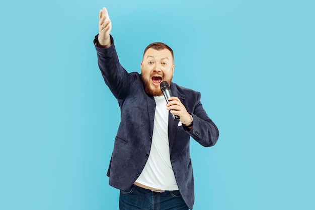 Free Photo young man with microphone on blue wall