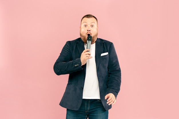 Free photo young man with microphone on pink, leading with microphone