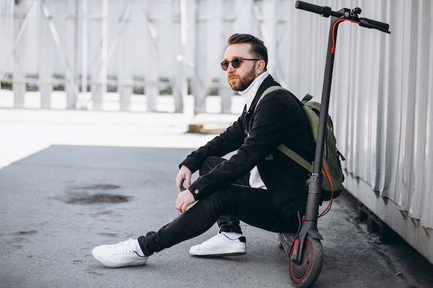 Free Photo young man with scooter, sitting on the ground