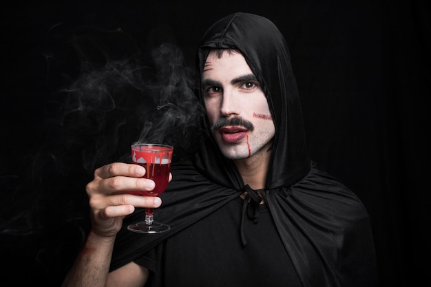 Young man with scratches on white face holding steaming drink