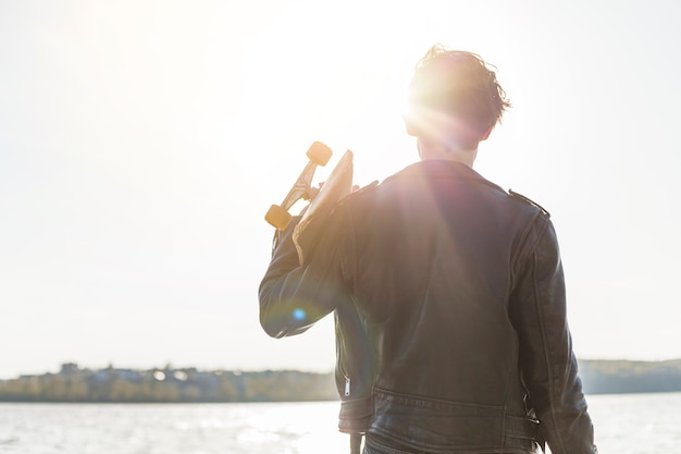 Young man with a skateboard near the sea