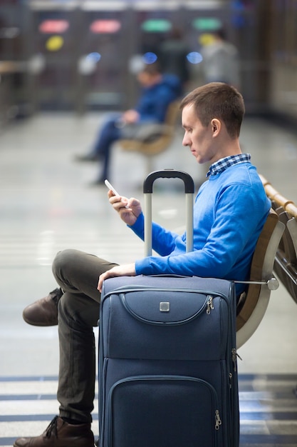 Free photo young man with smartphone waiting for transport