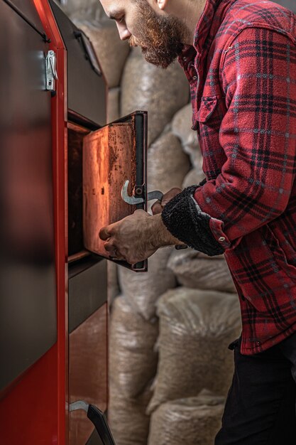 The young man with solid fuel boiler, working with biofuels, economical heating.