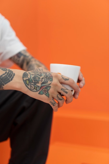 Free Photo young man with tattoos enjoying a cup of coffee at coffeehouse