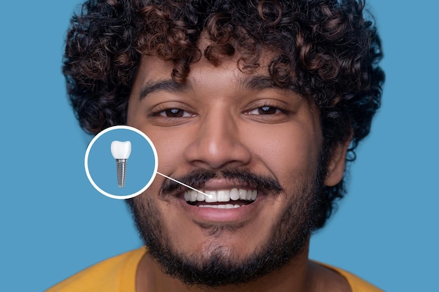 Free Photo young man with a toothy smile demonstrating his dental implant