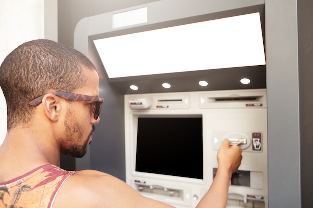 Free photo young man withdrawing money from atm