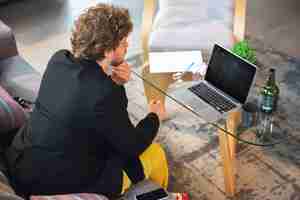 Free photo young man without pants but in jacket working on a computer, laptop.