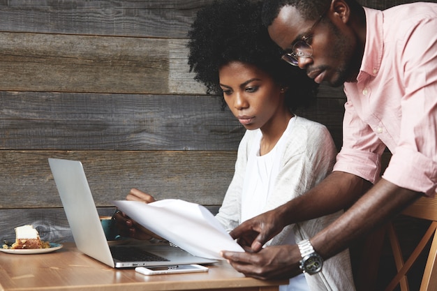 Young man and woman in cafe using laptop