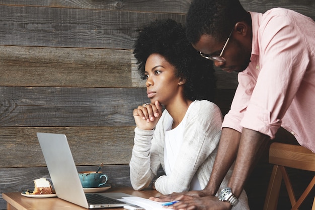 Young man and woman in cafe using laptop